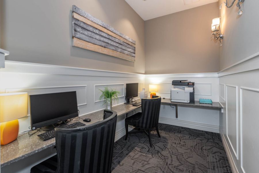 Attain at Quarterpath apartment homes with Modern office nook with two computer desks, chairs, a printer, lamps, and a wall art centerpiece.