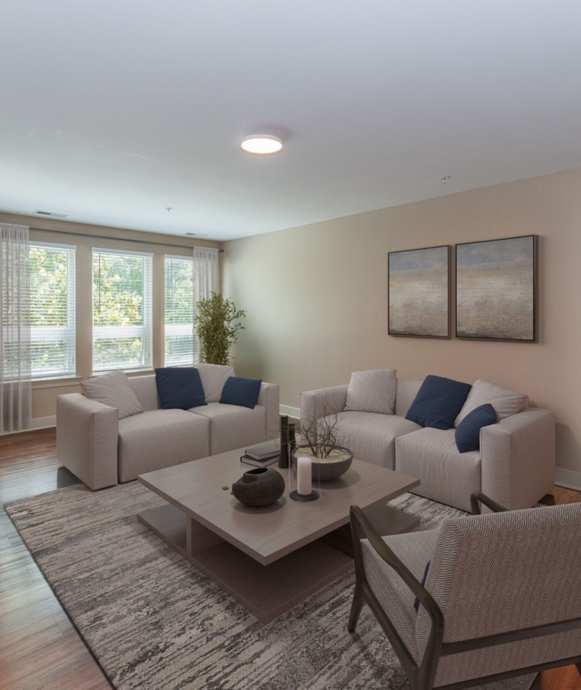 Attain on 5th apartment homes with Modern living room with beige walls, two sofas, armchair, coffee table, rug, large windows, and wooden floor.