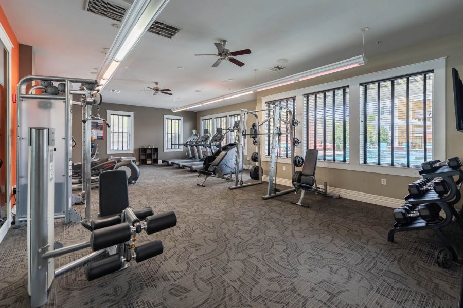 Attain at Quarterpath apartment homes with Modern gym with various cardio machines, weight equipment, and large windows letting in natural light.
