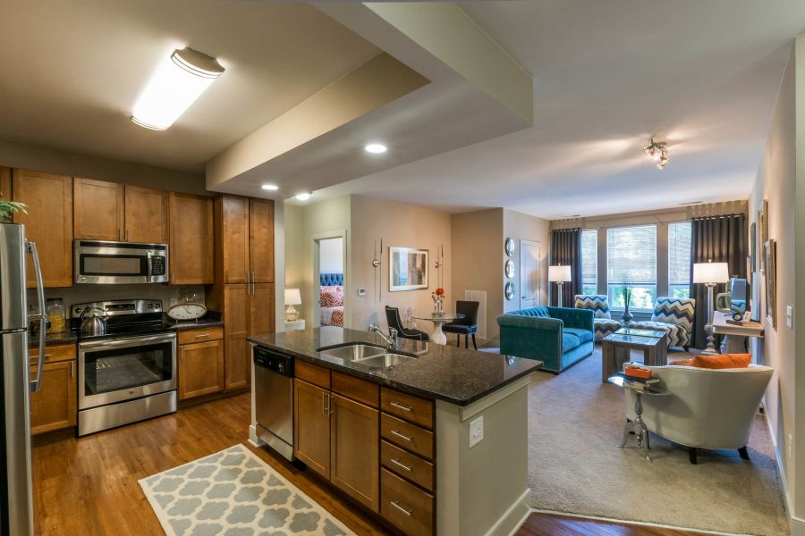 Attain at Quarterpath apartment homes with Modern open-concept kitchen and living room with wood cabinets, granite countertops, and cozy seating area.