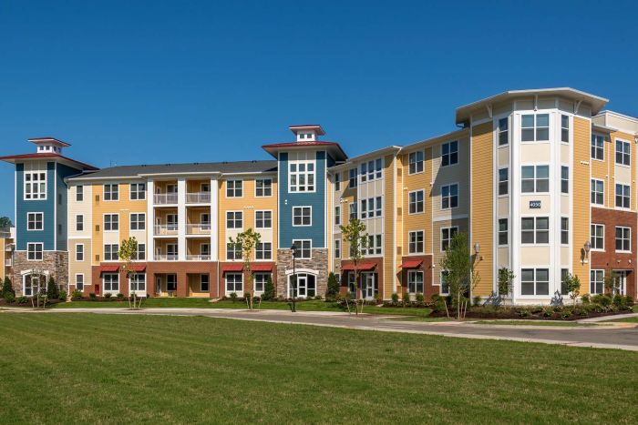Attain on 5th apartment homes with Colorful modern apartment building with multiple floors, large windows, and a neatly landscaped lawn in front.